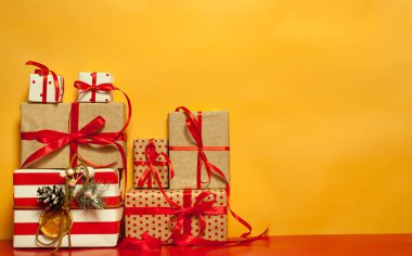 Parlak sarı arka plan üzerinde kırmızı yaylı hediye kutuları yığını 