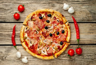 Ahşap arka plan üzerinde mantar, domates, zeytin ve jambon ile taze ev yapımı pizza