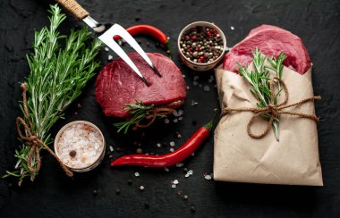 Çiğ taze biftek siyah taş arka plan üzerinde baharat ile kağıt sarılmış 