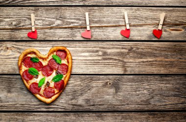 salam ve taze fesleğen yaprakları ve ahşap arka plan üzerinde kalpleri ile iğne ile peynir kalp pizza