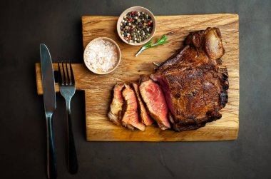 Siyah taş arka plan üzerinde ahşap doğrama tahtası üzerinde baharat ile Yağlı ızgara domuz biftek