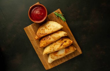 Ahşap doğrama tahtası üzerinde domates soslu Geleneksel Latin Amerika kızarmış empanadas 
