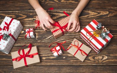 Eski ahşap arka plan üzerinde kırmızı yay ile kadın elleri dekorasyon hediye kutuları 