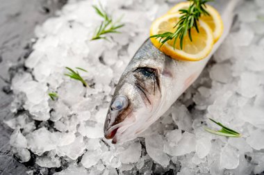 Soğuk ezilmiş buz yığını üzerinde limon dilimleri ve biberiye ile taze balık yakın görünümü