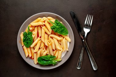 taş siyah arka plan üzerinde yeşil yaprakları ile servis domates soslu makarna