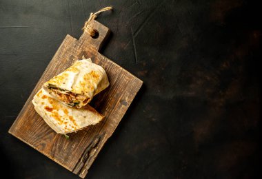 Ahşap doğrama tahtası üzerinde tavuk ve sebze ile sarılmış ev yapımı Meksika burrito 