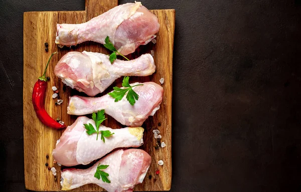 Ahşap doğrama tahtası üzerinde baharat, biber ve maydanoz yaprakları ile Tavuk bacakları 