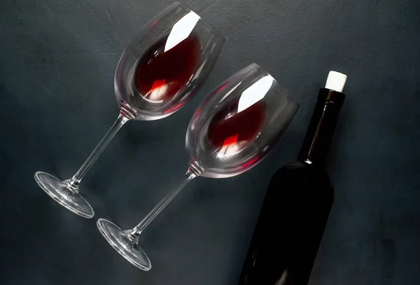 黒い背景に赤ワインとワインボトルのグラス2杯 — ストック写真