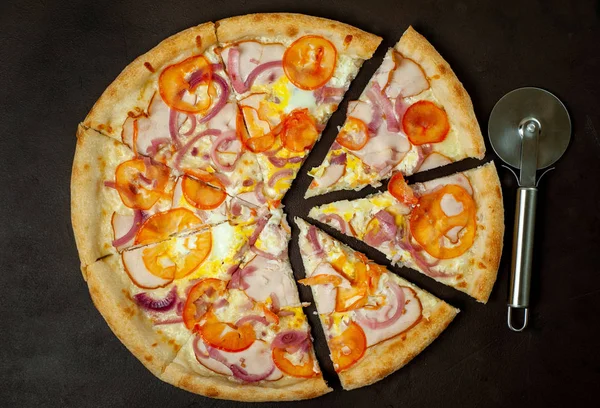 Fresh vegetable pizza with ham on black stone background