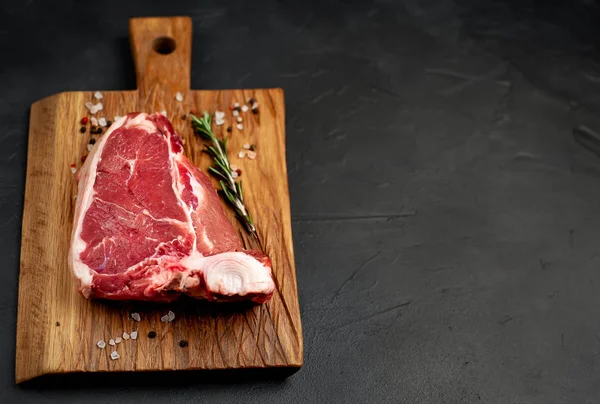 Tlustý Steak Kořením Rozmarní Větvičku Dřevěné Sekací Desce Nad Kamenným — Stock fotografie