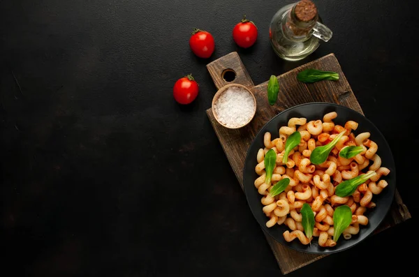 taş siyah arka plan üzerinde ahşap doğrama tahtası üzerinde domates soslu makarna