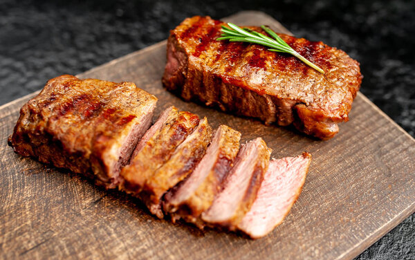 Grilled pork steaks with spices and rosemary on wooden chopping board
