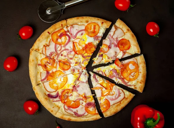 Fresh vegetable pizza with ham on black stone background