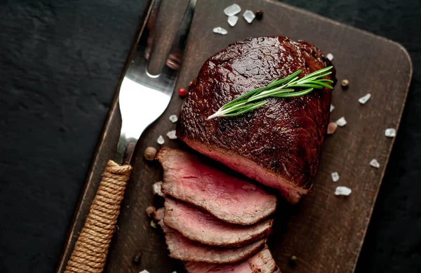 Siyah taş arka plan üzerinde baharat ve biberiye dal ile Taze ızgara biftek