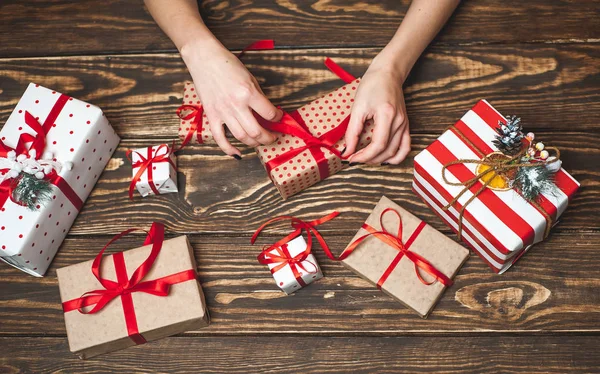 Eski ahşap arka plan üzerinde kırmızı yay ile kadın elleri dekorasyon hediye kutuları 