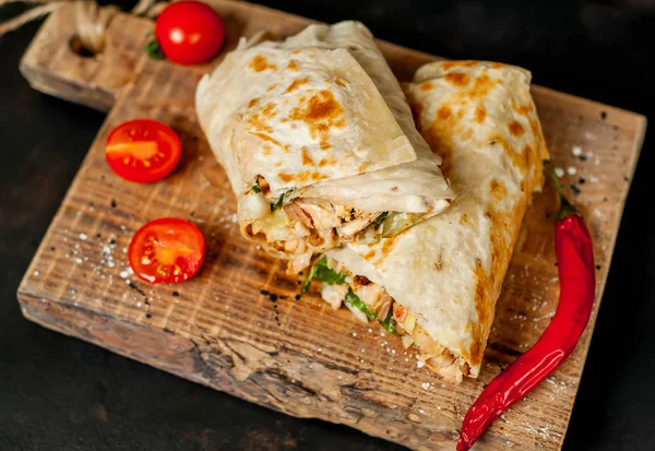 Geleneksel Meksika burrito tavuk ve sebze ile sarılmış ahşap doğrama tahtası üzerinde olgun domates ile servis 
