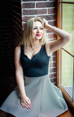 Vintage iç pencere üzerinde oturan şık sarışın kadın 