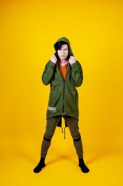 Parlak sarı arka planda poz veren şık genç adam. 