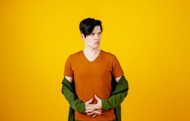 Parlak sarı arka planda poz veren şık genç adam. 