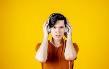 Young hipster man in headphones on bright yellow background 