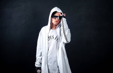 Genç şık esmer adam siyah arka planda mikrofonla poz veriyor.