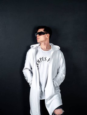 Siyah arka planda poz veren şık esmer bir adam.