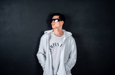 Siyah arka planda poz veren şık esmer bir adam.