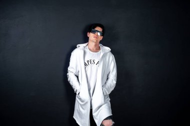 Siyah arka planda poz veren şık esmer bir adam.