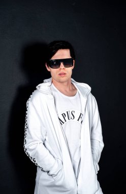 Siyah arka planda poz veren şık esmer bir adam.