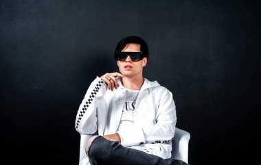 Siyah arka planda poz veren şık esmer bir adam.