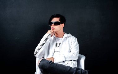 Siyah arka planda poz veren şık esmer bir adam.