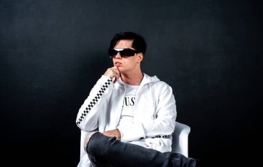 Siyah arka planda poz veren şık esmer bir adam.