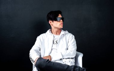 Siyah arka planda poz veren şık esmer bir adam.