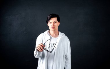 Siyah arka planda poz veren şık esmer bir adam.