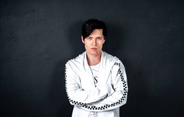 Siyah arka planda poz veren şık esmer bir adam.