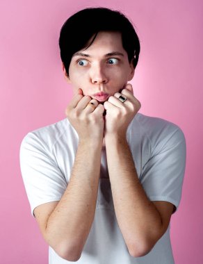 Genç esmer adam pastel pembe arka planda poz veriyor.