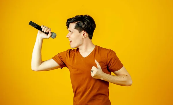 Parlak Sarı Arka Planda Mikrofonda Şarkı Söyleyen Şık Esmer Adam — Stok fotoğraf