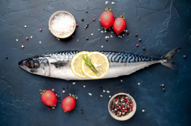 Siyah taş arka plan üzerinde limon dilimleri ve biberiye dalları ile çiğ balık