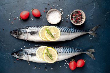 Siyah taş arka plan üzerinde limon dilimleri ve biberiye dalları ile çiğ balık