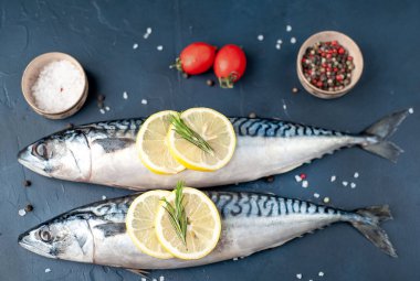 Siyah taş arka plan üzerinde limon dilimleri ve biberiye dalları ile çiğ balık