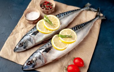 Siyah taş arka plan üzerinde limon dilimleri ve biberiye dalları ile çiğ balık