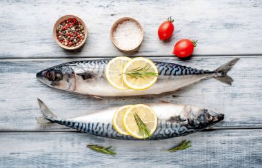 Gri ahşap arka plan üzerinde limon dilimleri ve biberiye dalları ile çiğ balık