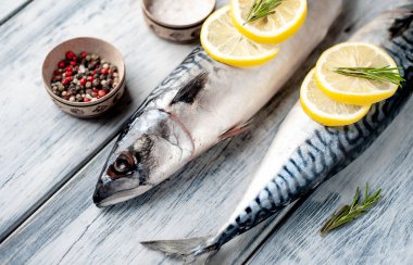 Gri ahşap arka plan üzerinde limon dilimleri ve biberiye dalları ile çiğ balık