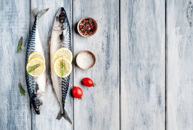 Gri ahşap arka plan üzerinde limon dilimleri ve biberiye dalları ile çiğ balık