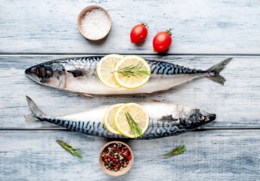 Gri ahşap arka plan üzerinde limon dilimleri ve biberiye dalları ile çiğ balık