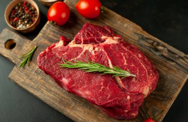 Ahşap doğrama tahtasında domates ve biberiye dal ile Taze çiğ biftek 