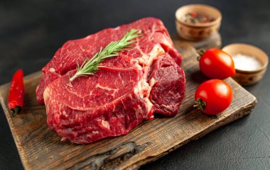 Ahşap doğrama tahtasında domates ve biberiye dal ile Taze çiğ biftek 