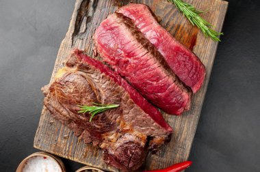 Siyah taş arka plan üzerinde ahşap doğrama tahtası üzerinde baharat ile Taze nadir ızgara beefsteak