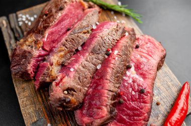 Siyah taş arka plan üzerinde ahşap doğrama tahtası üzerinde baharat ile Taze nadir ızgara beefsteak