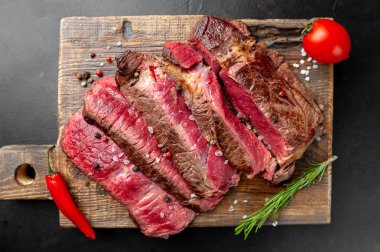 Siyah taş arka plan üzerinde ahşap doğrama tahtası üzerinde baharat ile Taze nadir ızgara beefsteak